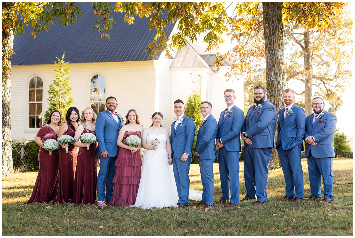 Burgundy and blue fall inspired bridal party outside Magnolia Country Chapel