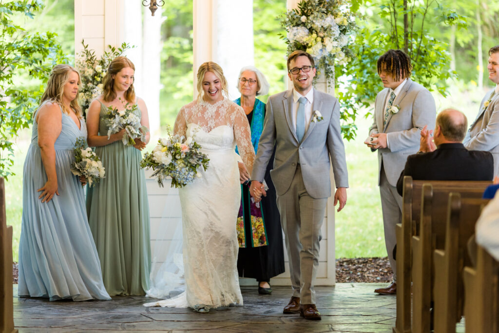 The bride and groom begin their recessional down the aisle of the white chapel at Firefly Lane